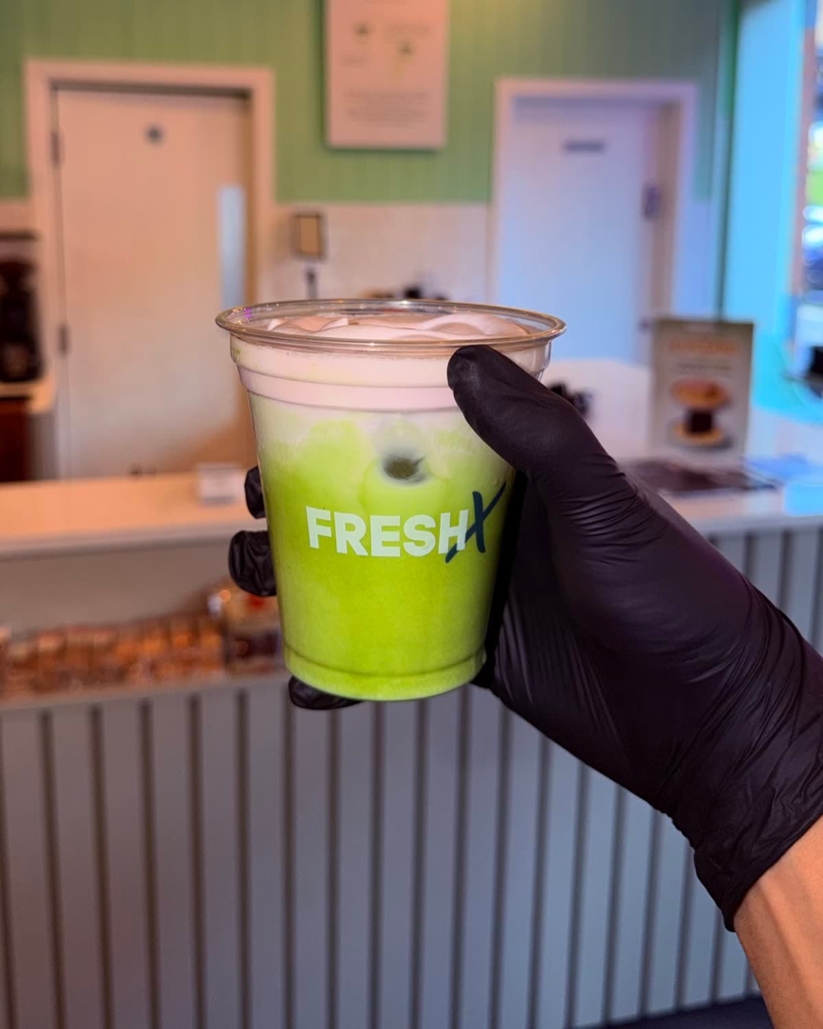 Strawberry matcha in a FreshX cup, held up at the counter