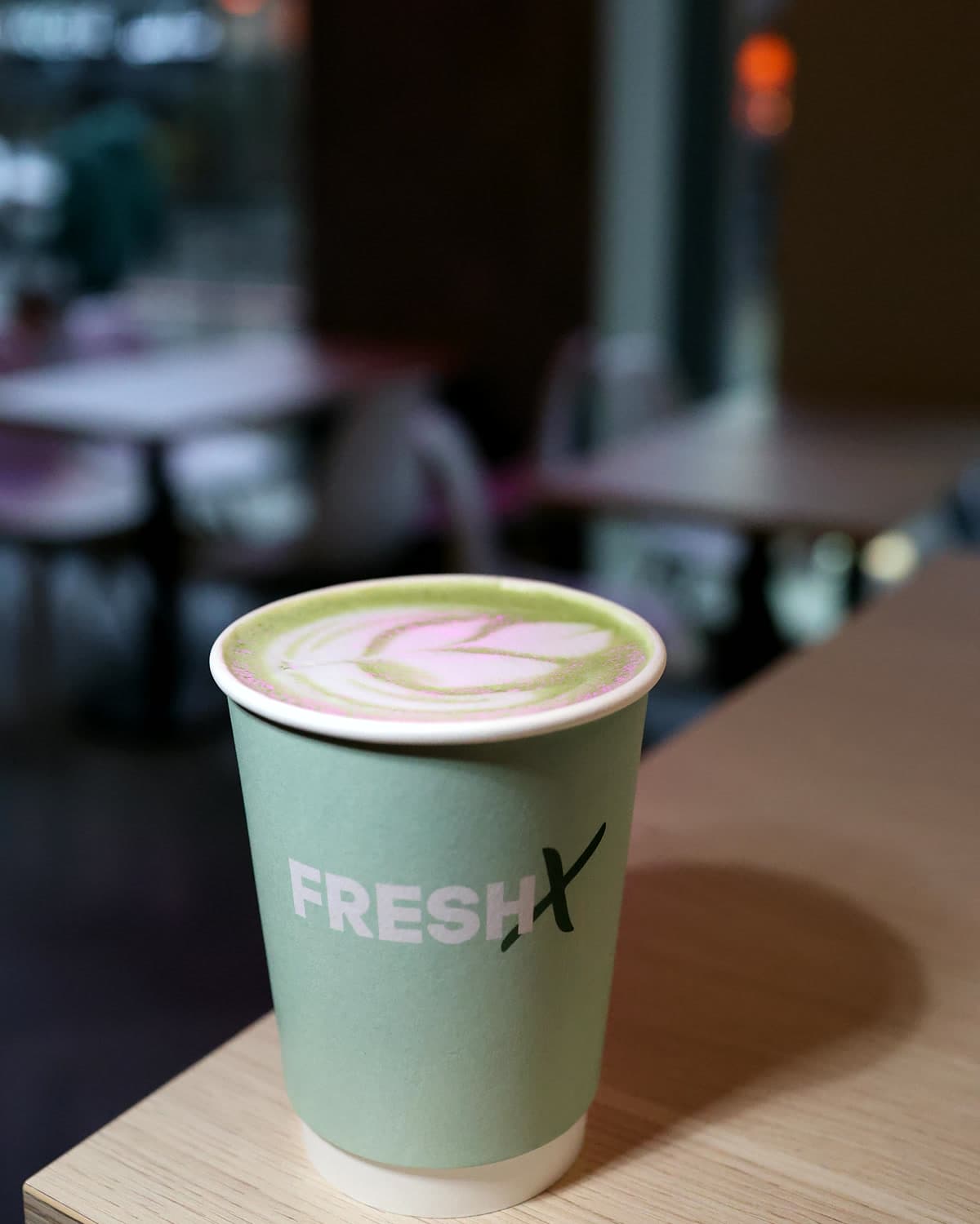 Strawberry matcha with latte art in a sage FreshX cup on the counter edge